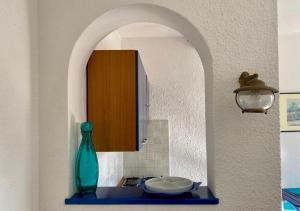 a kitchen with a green vase on a blue shelf at Lilli's House in Porto Santo Stefano