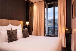 um quarto com uma cama grande e uma janela grande em First Hotel Paris Tour Eiffel em Paris