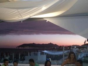 a group of people sitting under a white umbrella at Torre Del Sole in Terracina