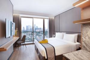 a hotel room with a bed and a large window at Somerset Sudirman Jakarta in Jakarta