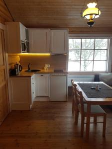 a kitchen with white cabinets and a table with chairs at Arina Cottages in Nasva