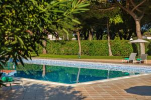 a swimming pool with two chairs and an umbrella at The Patio Suite Hotel in Albufeira