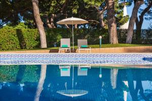 two chairs and an umbrella next to a swimming pool at The Patio Suite Hotel in Albufeira
