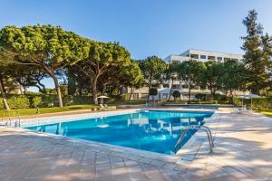 a swimming pool with trees and a building in the background at The Patio Suite Hotel in Albufeira