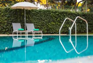 two chairs and an umbrella next to a swimming pool at The Patio Suite Hotel in Albufeira