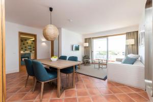 a dining room and living room with a table and chairs at The Patio Suite Hotel in Albufeira
