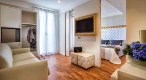 Sala de estar con sofá, cama y TV en Novecento Suite Hotel, en Riccione