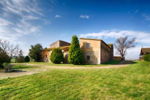 un antiguo edificio de piedra con árboles en un campo en Agroturisme Sant Dionis, en Campllong