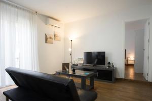 ein Wohnzimmer mit einem Sofa und einem Flachbild-TV in der Unterkunft La Luz del Falla Ha Apartment in Cádiz