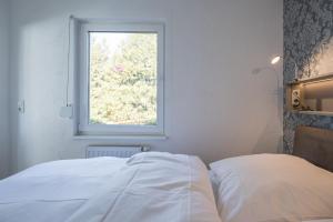 białe łóżko w pokoju z oknem w obiekcie Ferienhaus Rügenblick w mieście Stahlbrode