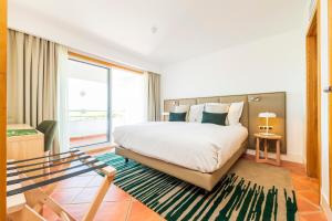a bedroom with a large bed and a large window at The Patio Suite Hotel in Albufeira