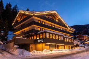 un gran edificio en la nieve por la noche en Luna Wellness Hotel, en Folgarida