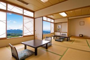 渋川市にあるいかほ秀水園のテーブル2台と椅子、大きな窓が備わる客室です。