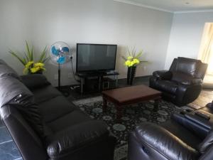 a living room with leather furniture and a flat screen tv at Seaside Retreat- Main House in Durban