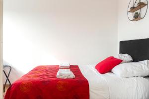 a bed with red and white sheets and pillows at Travel Homes - Le Rebberg, Superbe vue à Mulhouse in Mulhouse