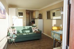 ein Wohnzimmer mit einem grünen Sofa und einem Tisch in der Unterkunft Sylt-Traum Meerblick in Westerland