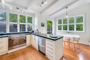 a kitchen with white cabinets and a table and chairs at Classic Villa Retreat - Steps To Ponsonby Rd in Auckland