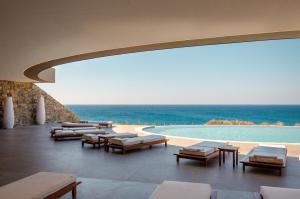 un complexe avec une piscine, des chaises longues et l'océan dans l'établissement ROBINSON Ierapetra, à Koutsounari