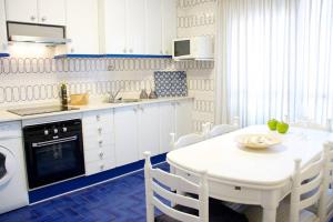 cocina blanca con mesa blanca, mesa y sillas en Piso en Lekeitio, Costa Vasca, Bizkaia., en Lekeitio