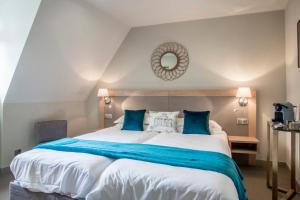 Les Sagranières في سيلارز: غرفة نوم مع سرير أبيض كبير مع وسائد زرقاء