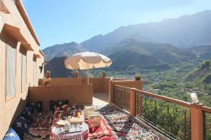 a balcony with a table and an umbrella at Imlil Authentic Toubkal Lodge in Imlil