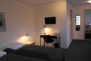 Schlafzimmer mit einem Bett und einem Schreibtisch mit einem Computer in der Unterkunft Skjoldbjerg Garnihotel in Vorbasse