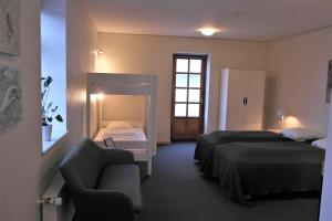 a bedroom with two beds and a couch and a chair at Skjoldbjerg Garnihotel in Vorbasse