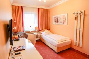 a small hotel room with a bed and a desk at Hotel Modena in Bad Steben