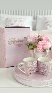 two cups and a plate with flowers and a box at Hotel Amadeus in České Budějovice