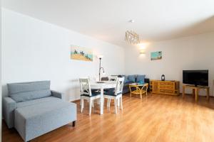 ein Wohnzimmer mit einem Tisch, einem Stuhl und einem Sofa in der Unterkunft Victus Apartamenty, Apartament Mewi Śpiew in Sopot