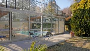 瓦朗索尔Les Chambres d Hôtes de Valensole au pays des lavandes et proche des Gorges du Verdon的一座玻璃建筑,前面设有桌椅