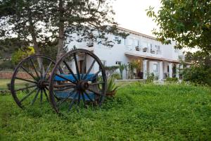 an old wagon wheel in the grass in front of a house at Apartamentos Vista Vedrá in La Savina