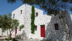 a white building with a red door and ivy on it at Anezina Village in Drios