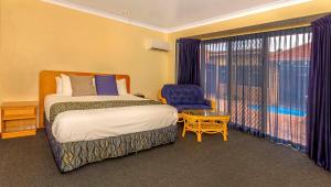 ein Schlafzimmer mit einem Bett und einem Stuhl und einem Fenster in der Unterkunft Comfort Inn Bay of Isles in Esperance