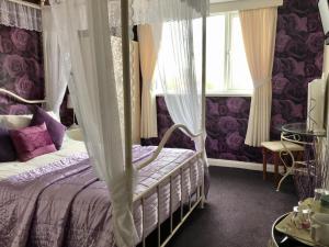 a purple bedroom with a canopy bed and a window at The Sunningdale in Skegness