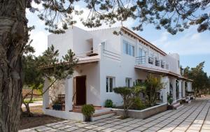 a white house with a tree in front of it at Apartamentos Vista Vedrá in La Savina