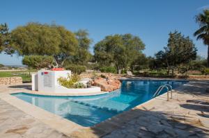 a pool at a resort with trees in the background at Apartamentos Vista Vedrá in La Savina