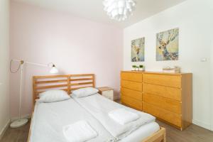 a bedroom with a bed and a wooden dresser at Victus Apartamenty, Apartament Malta in Sopot