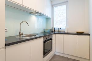 a kitchen with white cabinets and a sink and a window at Victus Apartamenty, Apartament Malta in Sopot