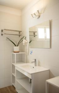 a white bathroom with a sink and a mirror at Apartamentos Vista Vedrá in La Savina