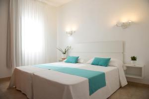 a bed with two blue pillows on top of it at Apartamentos Vista Vedrá in La Savina