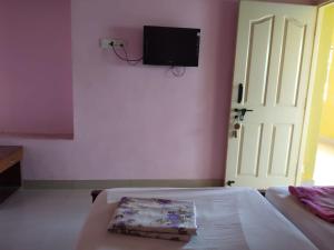 a bedroom with a bed and a tv on a wall at Hotel Blue Coral Rameswaram in Rāmeswaram