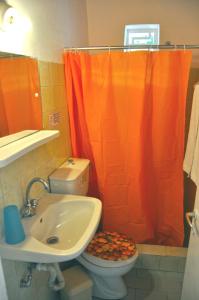 La salle de bains est pourvue d'un rideau de douche orange et de toilettes. dans l'établissement Villa Elena Studios, à Dassia