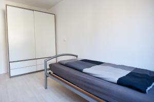 - une chambre avec un lit et un mur blanc dans l'établissement Work and Stay Apartment in Troisdorf, à Troisdorf