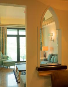 a living room with a mirror and a couch at Retaj Salwa Resort & Spa in Doha