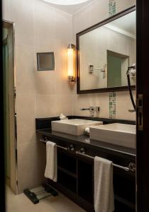 a bathroom with two sinks and a large mirror at Retaj Salwa Resort & Spa in Doha