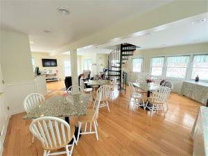 a living room with tables and white chairs at The Escape Inn in South Yarmouth