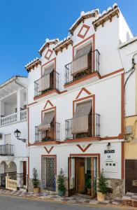 a white building with balconies on a street at Casa Rural Del Rio in Alozaina