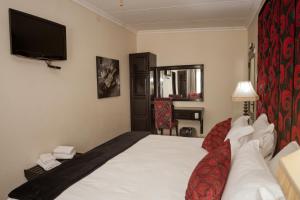 a hotel room with a bed and a flat screen tv at Silverton Travel Lodge in Pretoria