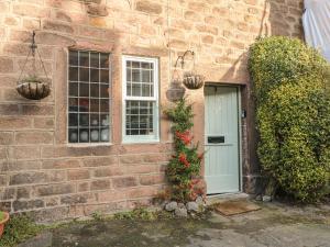 a brick house with a white door and flowers at North Street Cottage in Matlock